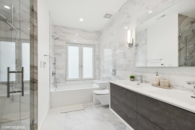 full bathroom with tile walls, separate shower and tub, toilet, and vanity