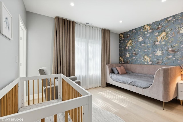 bedroom with recessed lighting, an accent wall, and wood finished floors