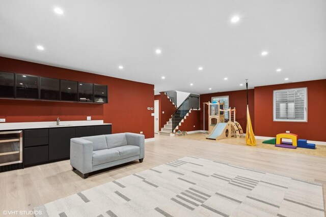 interior space with beverage cooler, sink, and light hardwood / wood-style floors