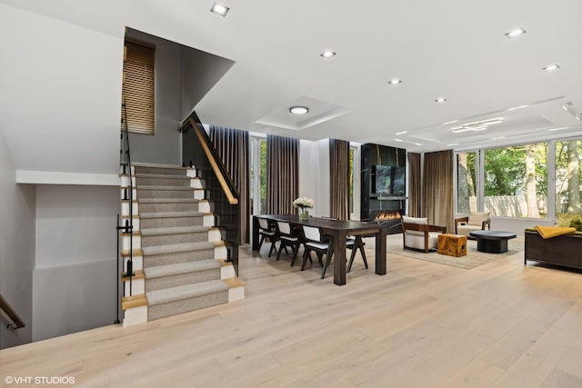 dining room with stairs, a healthy amount of sunlight, light wood-type flooring, and expansive windows
