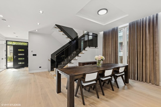 dining room with plenty of natural light, light wood-style flooring, stairs, and baseboards