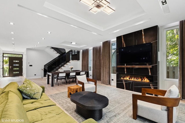 living room with a wealth of natural light, a raised ceiling, and stairs