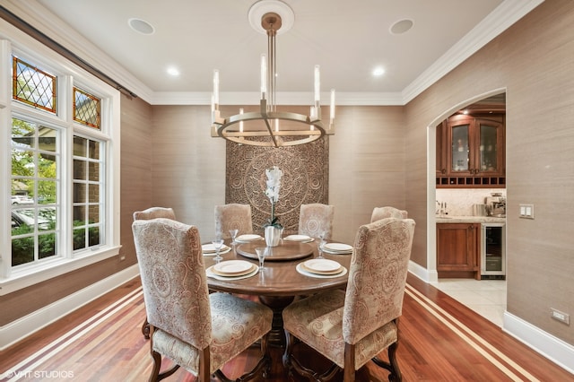 dining area featuring beverage cooler, light tile patterned floors, a wealth of natural light, and crown molding