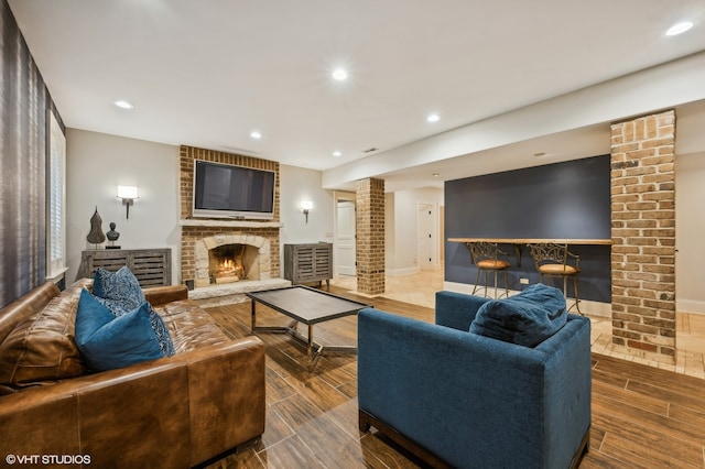 living room with a fireplace, wood-type flooring, and ornate columns