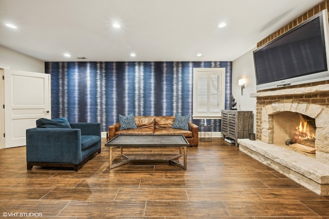 living room with dark hardwood / wood-style flooring and a stone fireplace