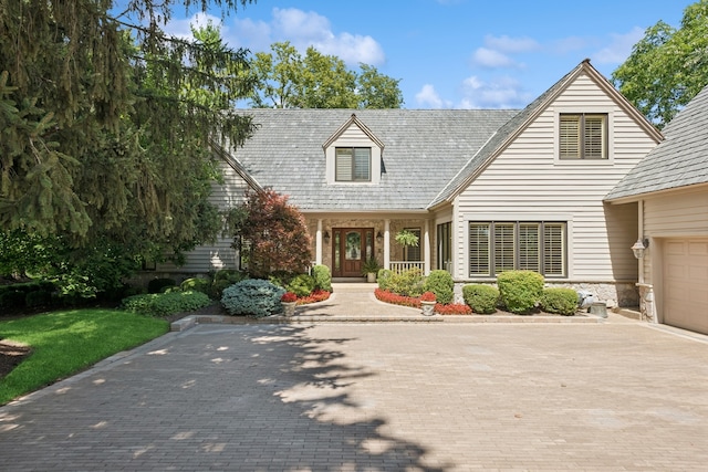 new england style home featuring a garage and covered porch