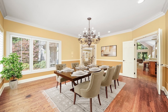 dining area with hardwood / wood-style flooring, ornamental molding, and a chandelier