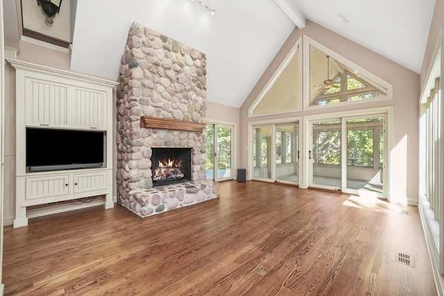 unfurnished living room with hardwood / wood-style floors, beam ceiling, a wealth of natural light, and high vaulted ceiling