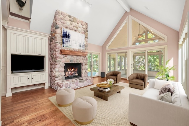 living room featuring a fireplace, plenty of natural light, beamed ceiling, and light wood-type flooring