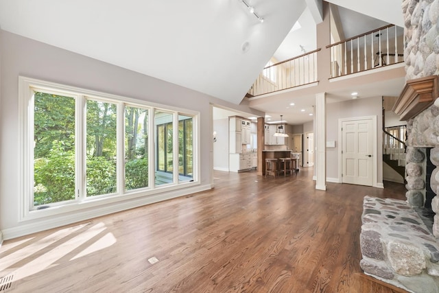 unfurnished living room featuring a healthy amount of sunlight, dark hardwood / wood-style floors, and high vaulted ceiling