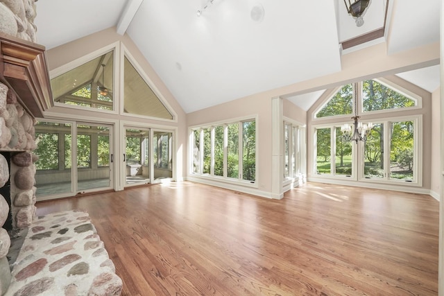 unfurnished sunroom featuring a stone fireplace, vaulted ceiling with beams, and an inviting chandelier