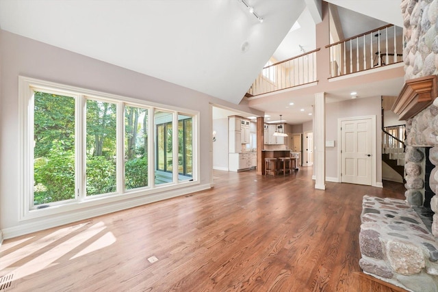 unfurnished living room with wood-type flooring, high vaulted ceiling, and a wealth of natural light