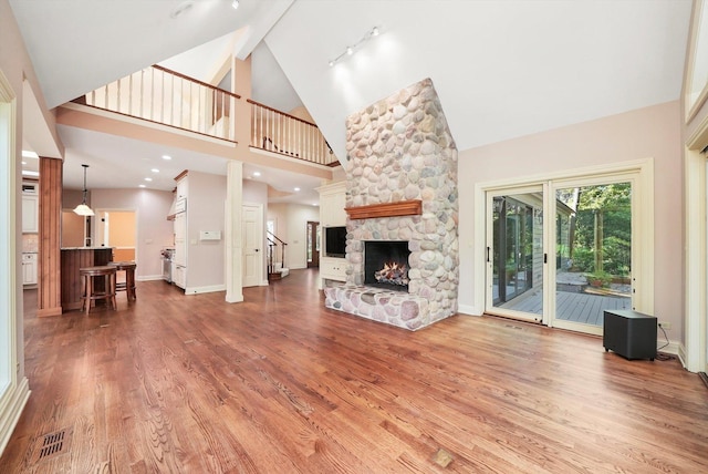 unfurnished living room with rail lighting, hardwood / wood-style floors, a fireplace, and high vaulted ceiling