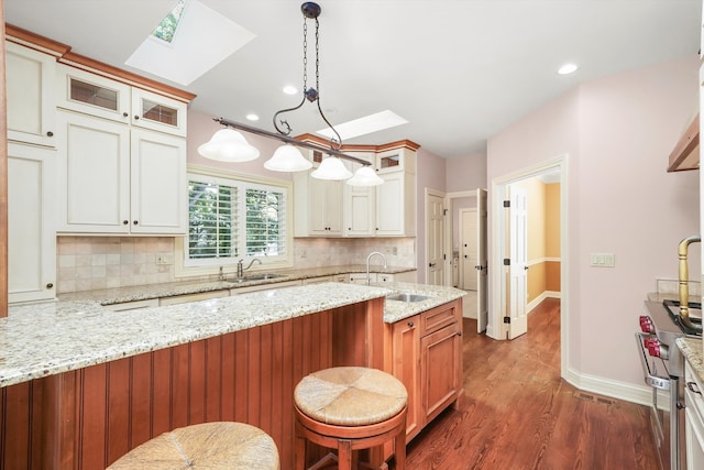 kitchen featuring pendant lighting, light stone countertops, sink, and backsplash