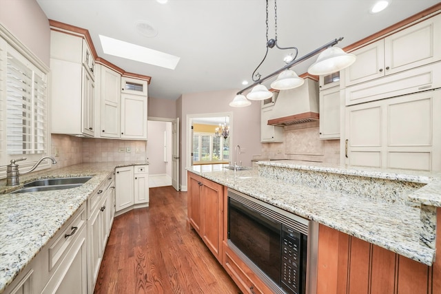 kitchen with white cabinetry, sink, decorative light fixtures, and light stone counters