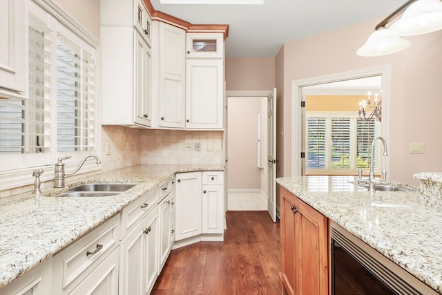 kitchen featuring white cabinetry, sink, hanging light fixtures, and backsplash