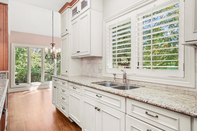 kitchen featuring sink, decorative light fixtures, light stone countertops, decorative backsplash, and white cabinets