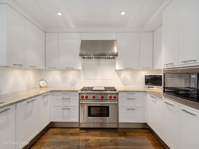 kitchen with decorative backsplash, white cabinets, dark hardwood / wood-style floors, wall chimney range hood, and luxury range