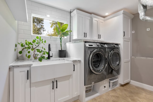 washroom featuring sink, washing machine and clothes dryer, and cabinets