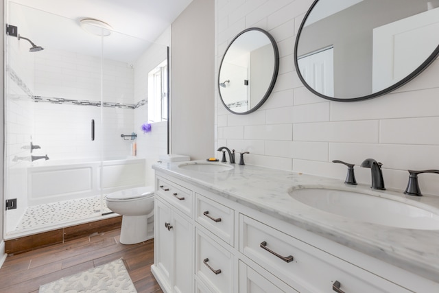 full bathroom with tile walls, vanity, wood-type flooring, shower / bath combination with glass door, and toilet