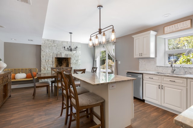 kitchen with a stone fireplace, dishwasher, dark hardwood / wood-style flooring, and white cabinets