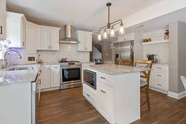 kitchen featuring dark wood-type flooring, white cabinets, a kitchen island, wall chimney exhaust hood, and stainless steel appliances