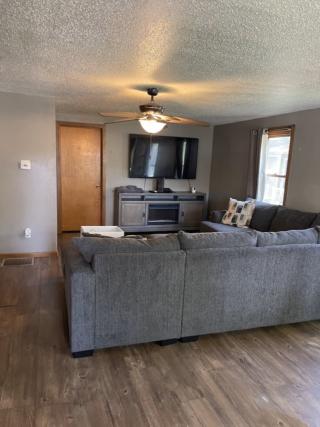 living room featuring a textured ceiling, ceiling fan, and dark hardwood / wood-style floors