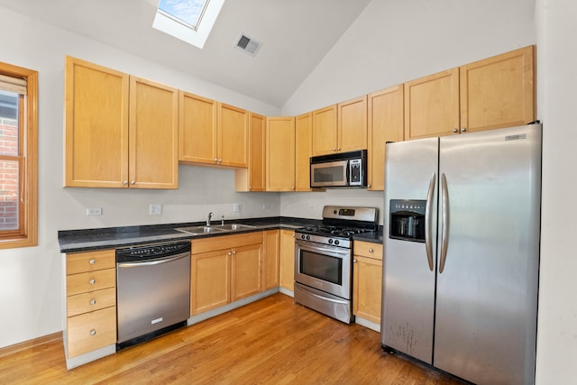 kitchen with sink, light hardwood / wood-style flooring, stainless steel appliances, a skylight, and light brown cabinetry