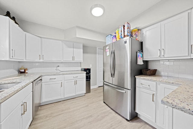 kitchen featuring light hardwood / wood-style flooring, stainless steel appliances, decorative backsplash, light stone counters, and white cabinets