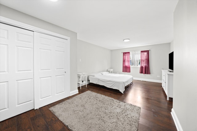 bedroom with dark wood-type flooring and a closet