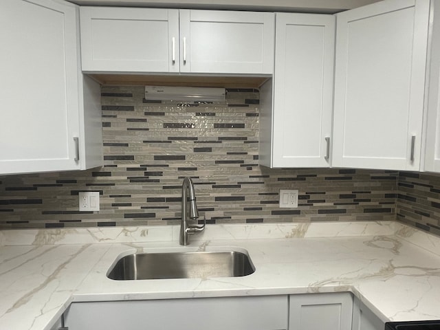 kitchen with white cabinetry, light stone counters, sink, and tasteful backsplash