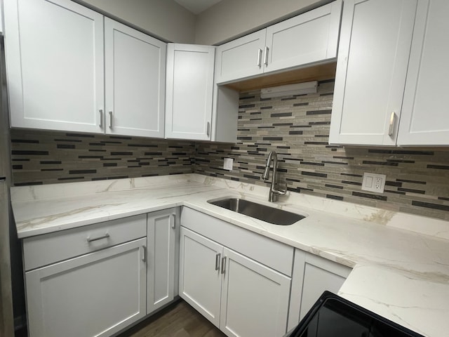 kitchen featuring light stone countertops, white cabinetry, sink, dark hardwood / wood-style floors, and decorative backsplash