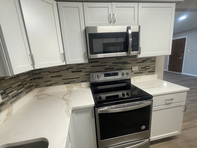 kitchen with appliances with stainless steel finishes, dark hardwood / wood-style flooring, and tasteful backsplash