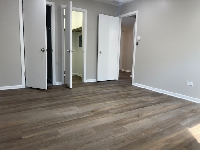 unfurnished bedroom featuring a closet, a walk in closet, and dark hardwood / wood-style floors