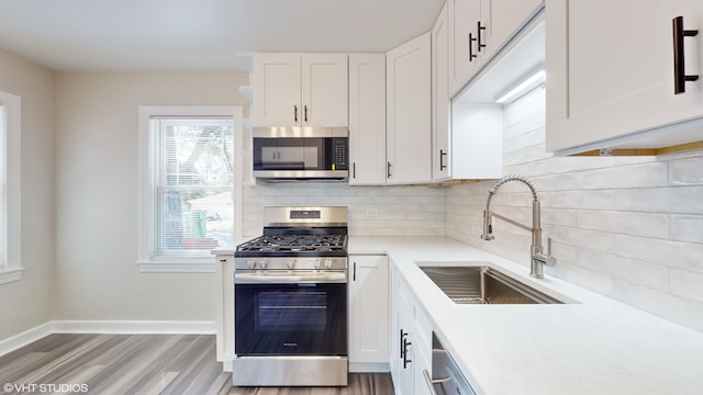 kitchen with backsplash, stainless steel appliances, light hardwood / wood-style floors, white cabinetry, and sink