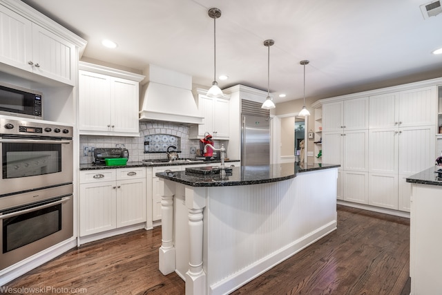 kitchen featuring premium range hood, dark hardwood / wood-style flooring, stainless steel appliances, and white cabinets