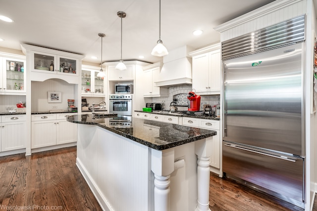 kitchen featuring dark wood-type flooring, hanging light fixtures, appliances with stainless steel finishes, and white cabinetry