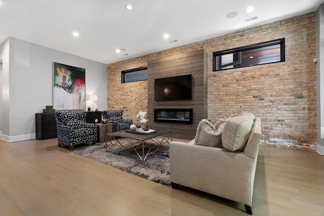 living room with brick wall, a fireplace, and hardwood / wood-style floors