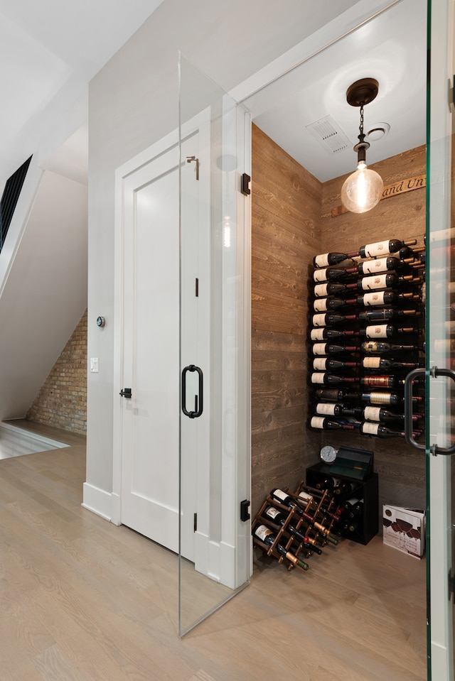 wine cellar with wood walls, hardwood / wood-style floors, and brick wall