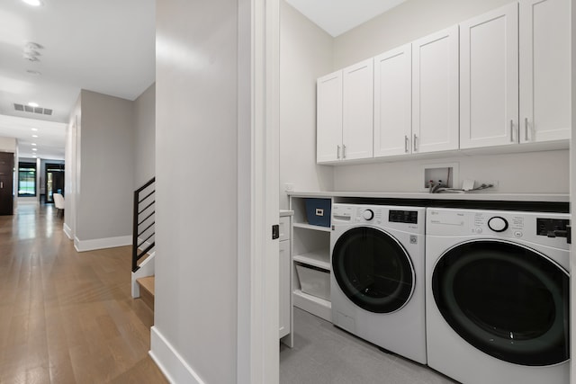 washroom featuring cabinets, light hardwood / wood-style flooring, and independent washer and dryer