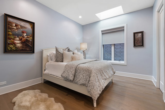 bedroom with hardwood / wood-style floors and a skylight