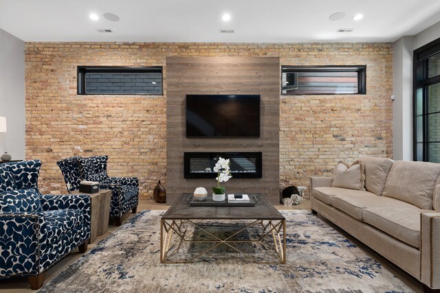 living room featuring wood-type flooring and brick wall