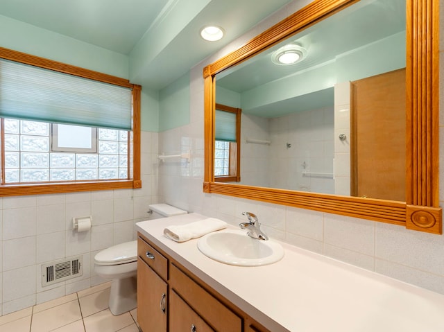 bathroom with tile walls, toilet, a wealth of natural light, and vanity