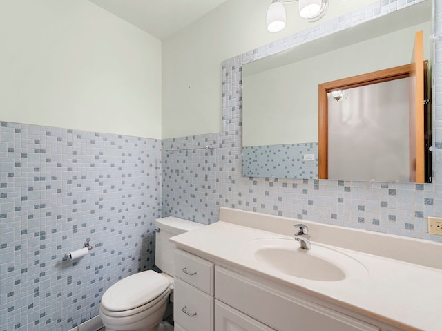 bathroom featuring vanity, toilet, and tile walls