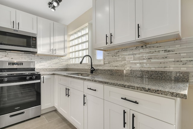 kitchen featuring sink, stone countertops, white cabinetry, stainless steel appliances, and decorative backsplash