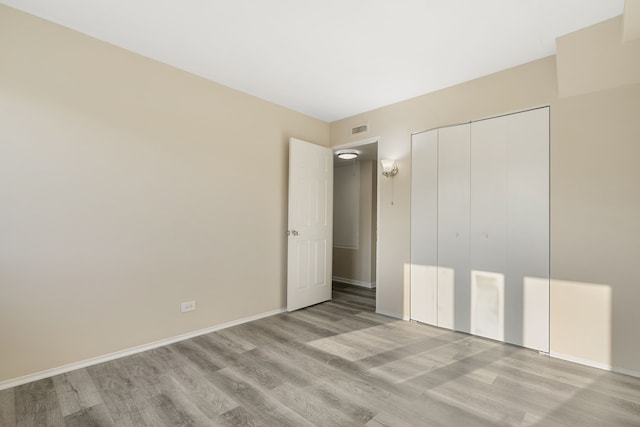 unfurnished bedroom featuring light hardwood / wood-style flooring and a closet