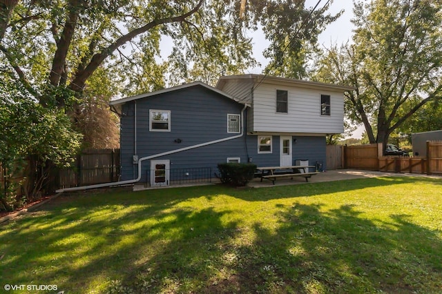 rear view of house featuring a lawn and a patio