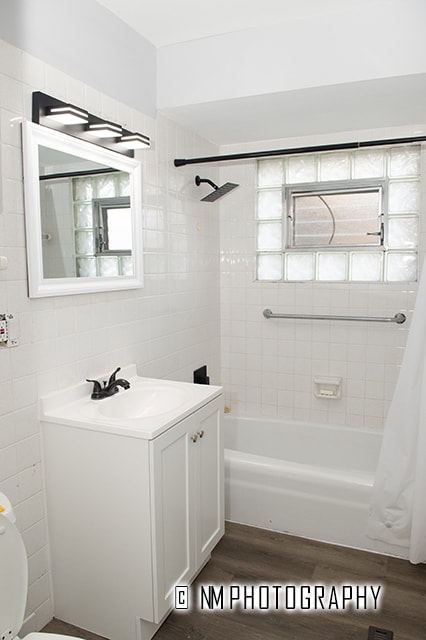 full bathroom with shower / bath combination with curtain, vanity, toilet, tile walls, and hardwood / wood-style floors