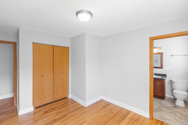 unfurnished bedroom with light hardwood / wood-style flooring, ensuite bath, and a closet