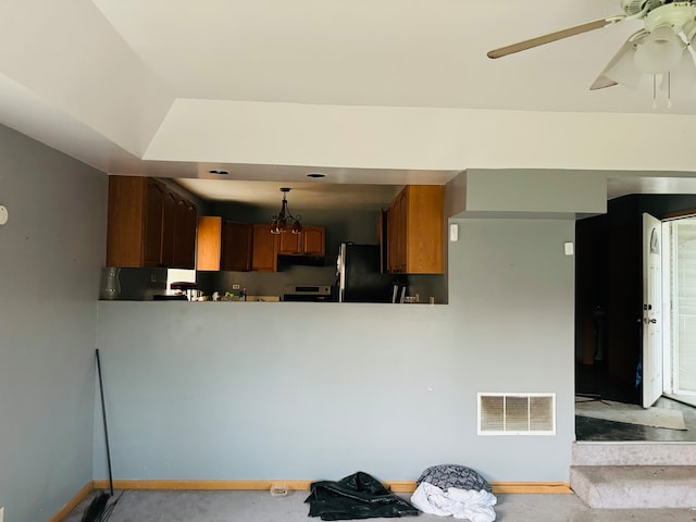 kitchen featuring pendant lighting, stainless steel stove, kitchen peninsula, ceiling fan, and black fridge